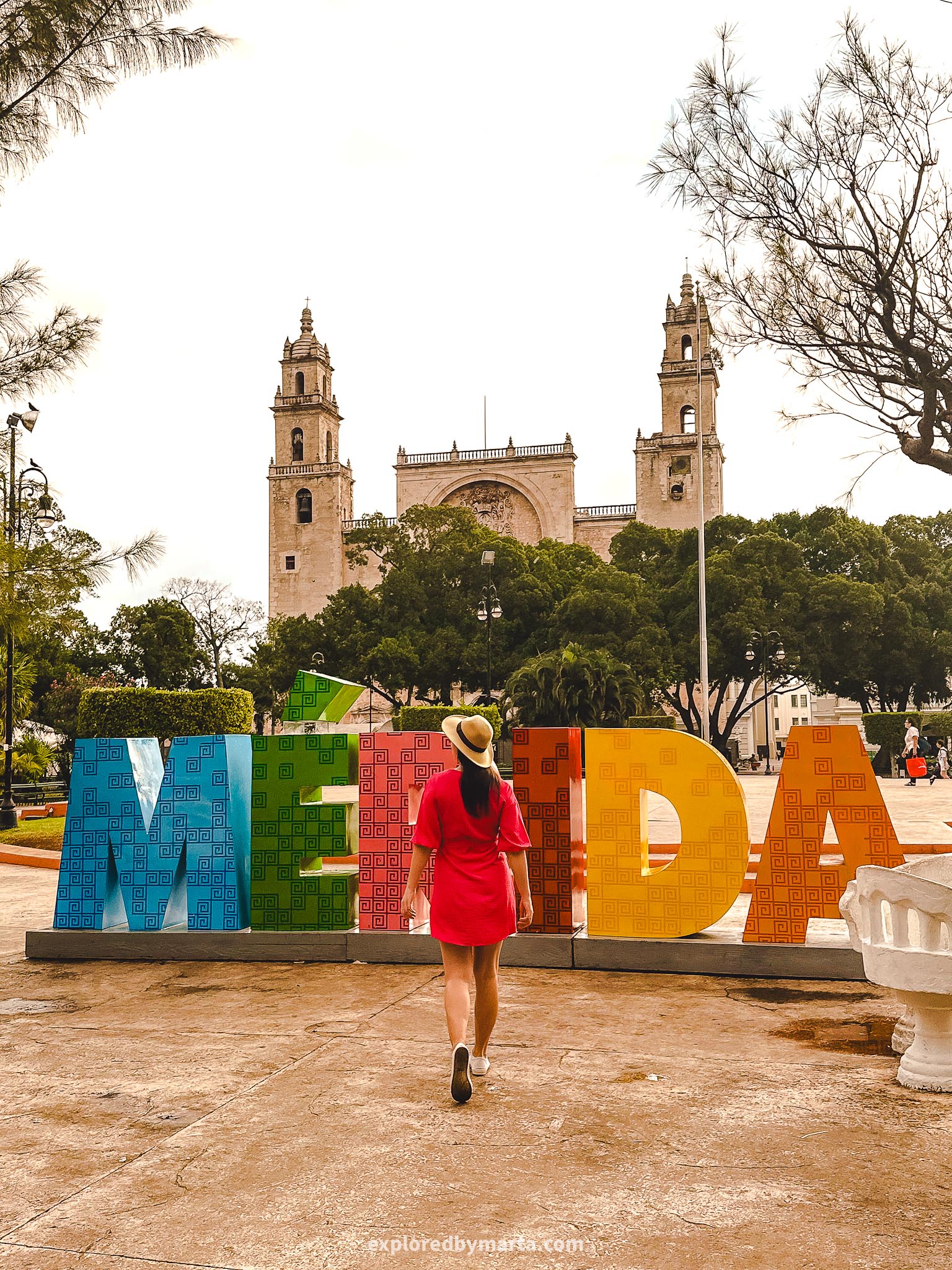 Best Instagram spots in Merida, Mexico - the colorful Merida letters in Plaza Grande park with the Cathedral of Merida towers in the background