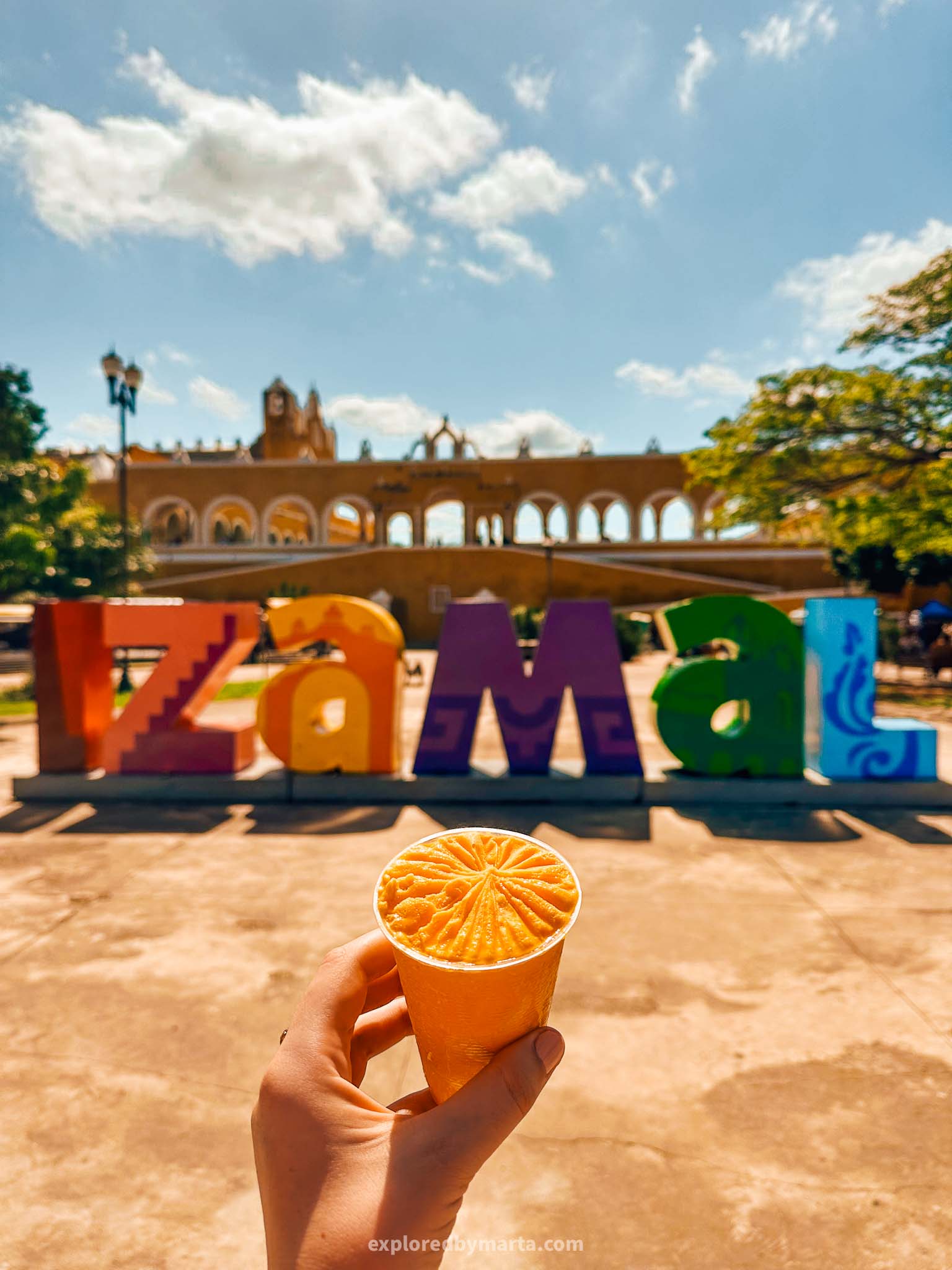 Izamal, Mexico-the yellow corn ice cream in a cup in Mexicos yellow city Izamal with the yellow Convento de San Antonio convent in the background