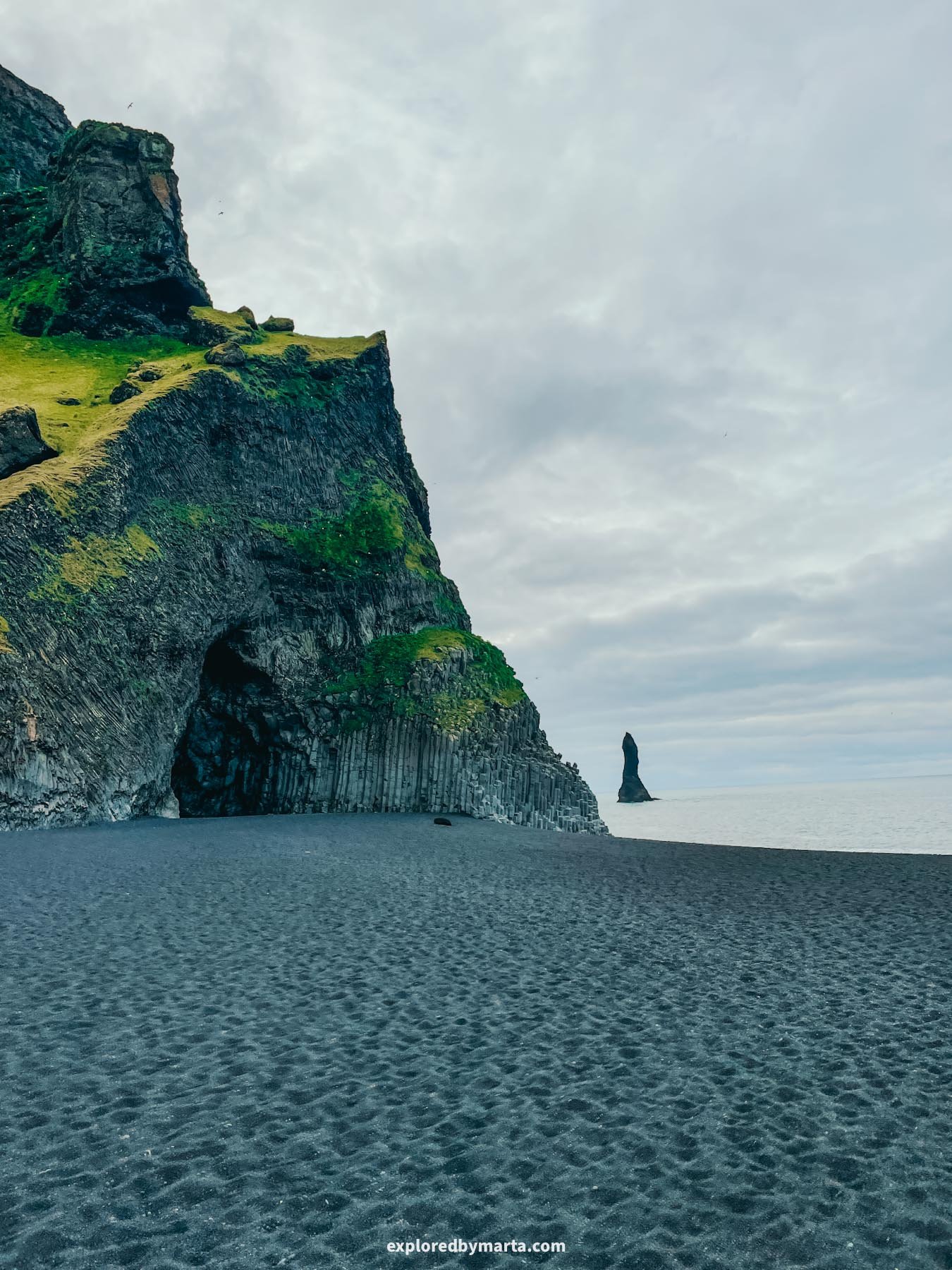 Reynisfjara Black sand beach in Iceland features a basalt column cave