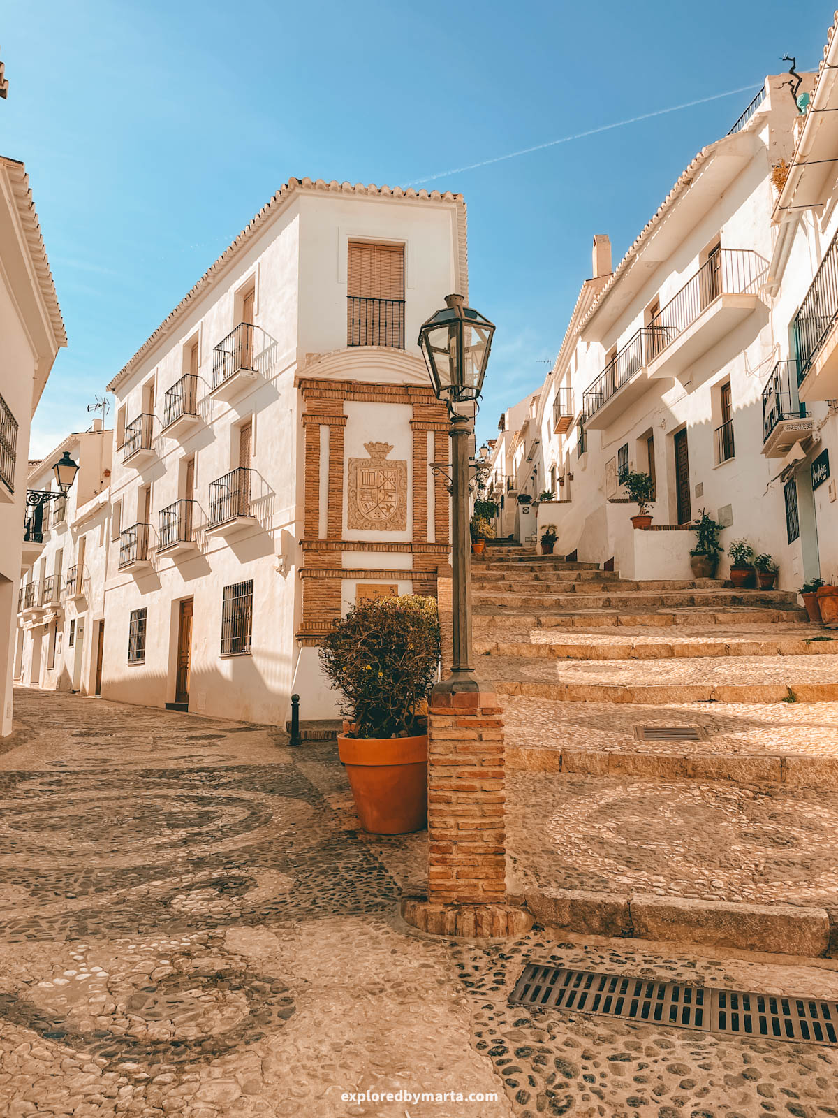 Coat of arms and a fountain on Calle Real in Frigiliana, Spain