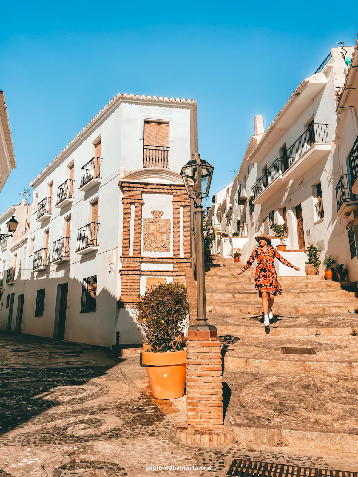 Coat of arms and a fountain on Calle Real in Frigiliana, Spain