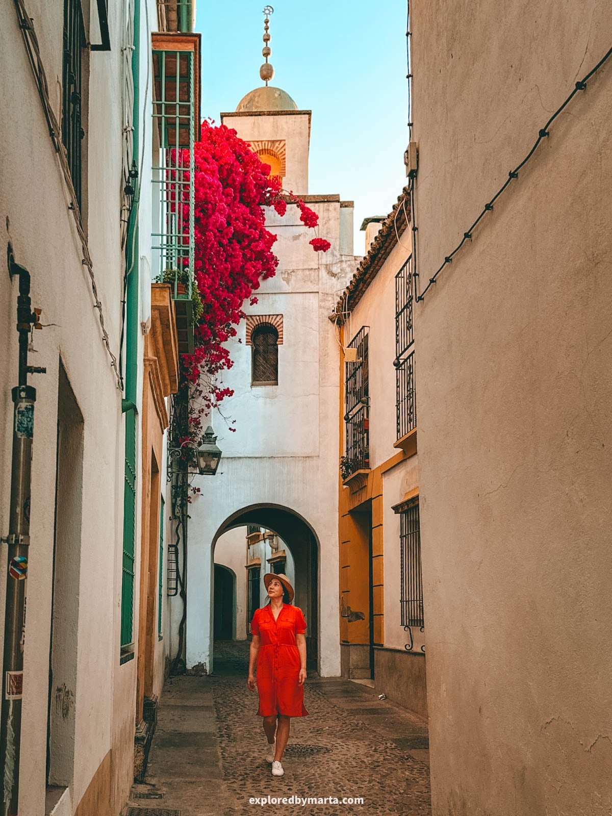 Walking under an old minaret on Calleja de la Hoguera in Córdoba, Spain