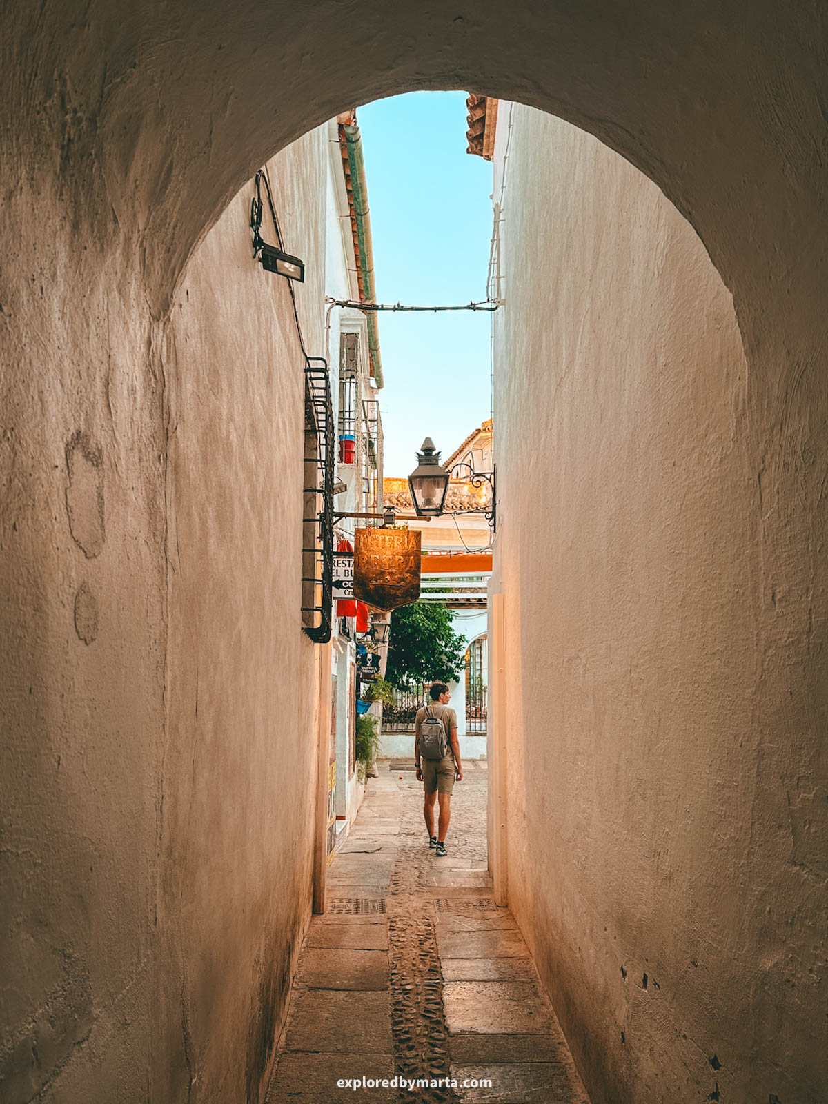 Walking under an old minaret on Calleja de la Hoguera in Córdoba, Spain