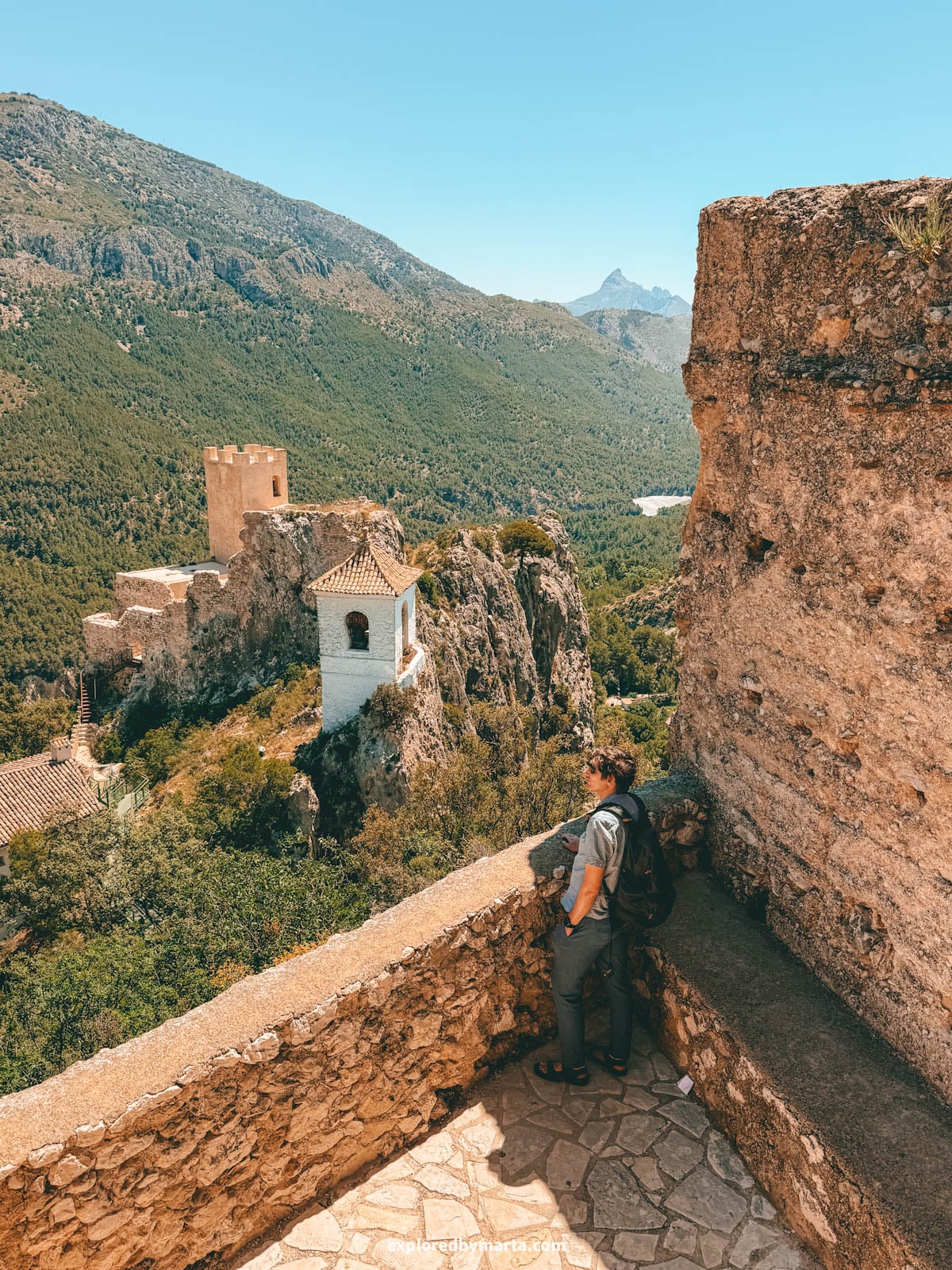 Looking out at the Guadalest bell tower and castle from San José castle in Guadalest, Spain
