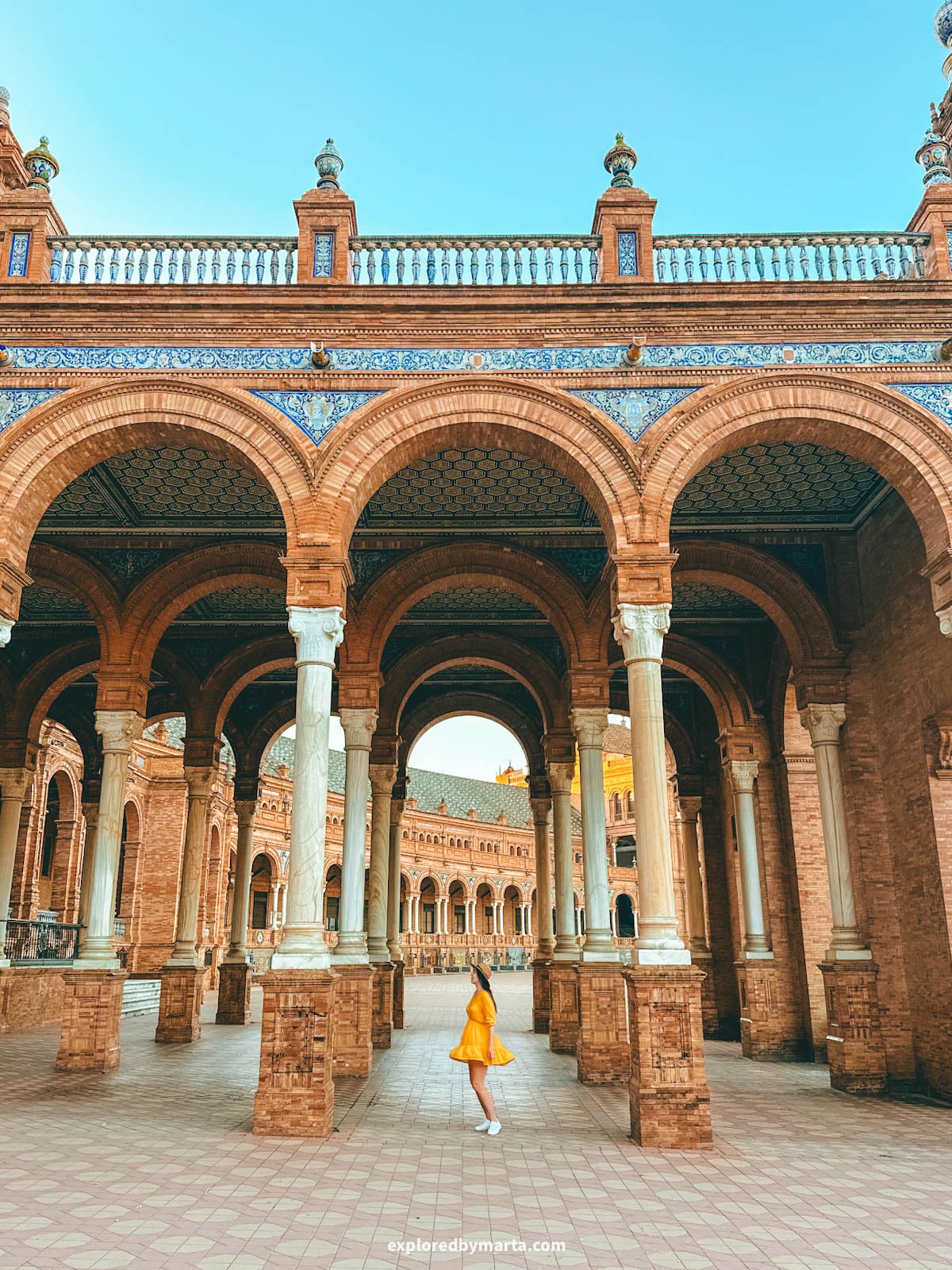 Standing under the arched walkway at Plaza de España in Seville Spain