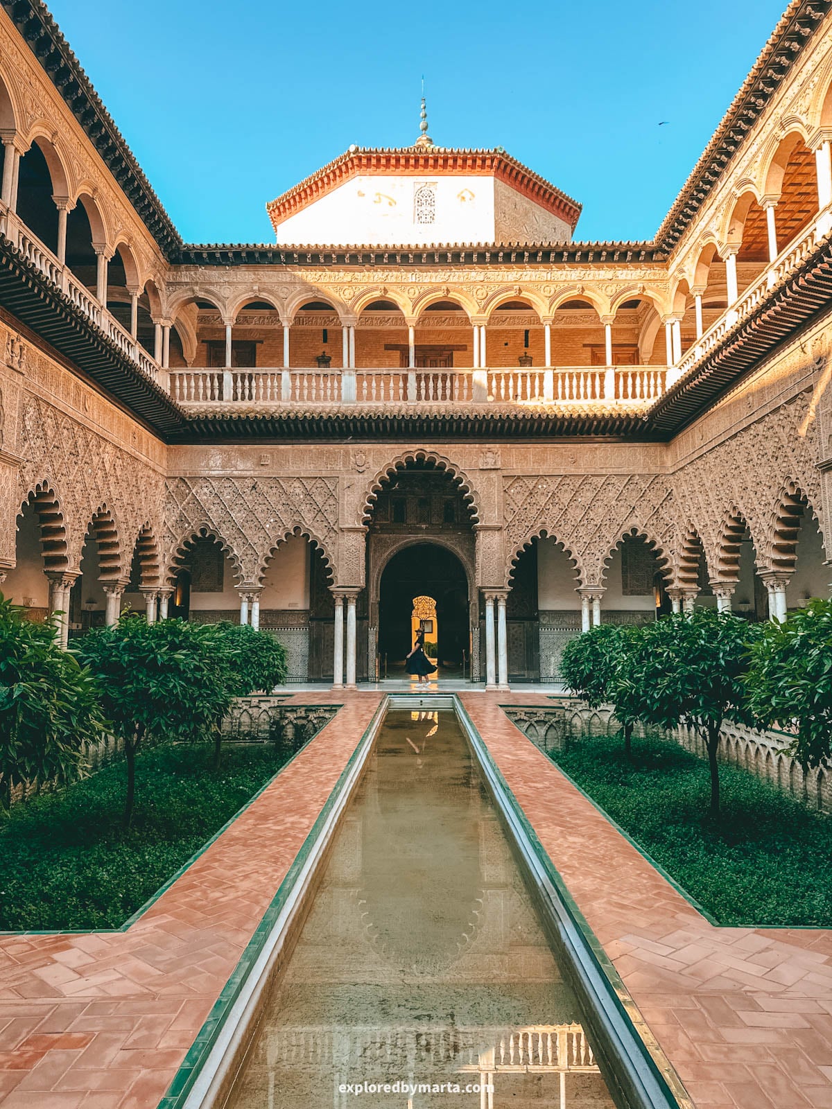 The Patio de las Doncellas with its reflecting pool and Mudéjar arches at the Royal Alcázar of Seville, Spain