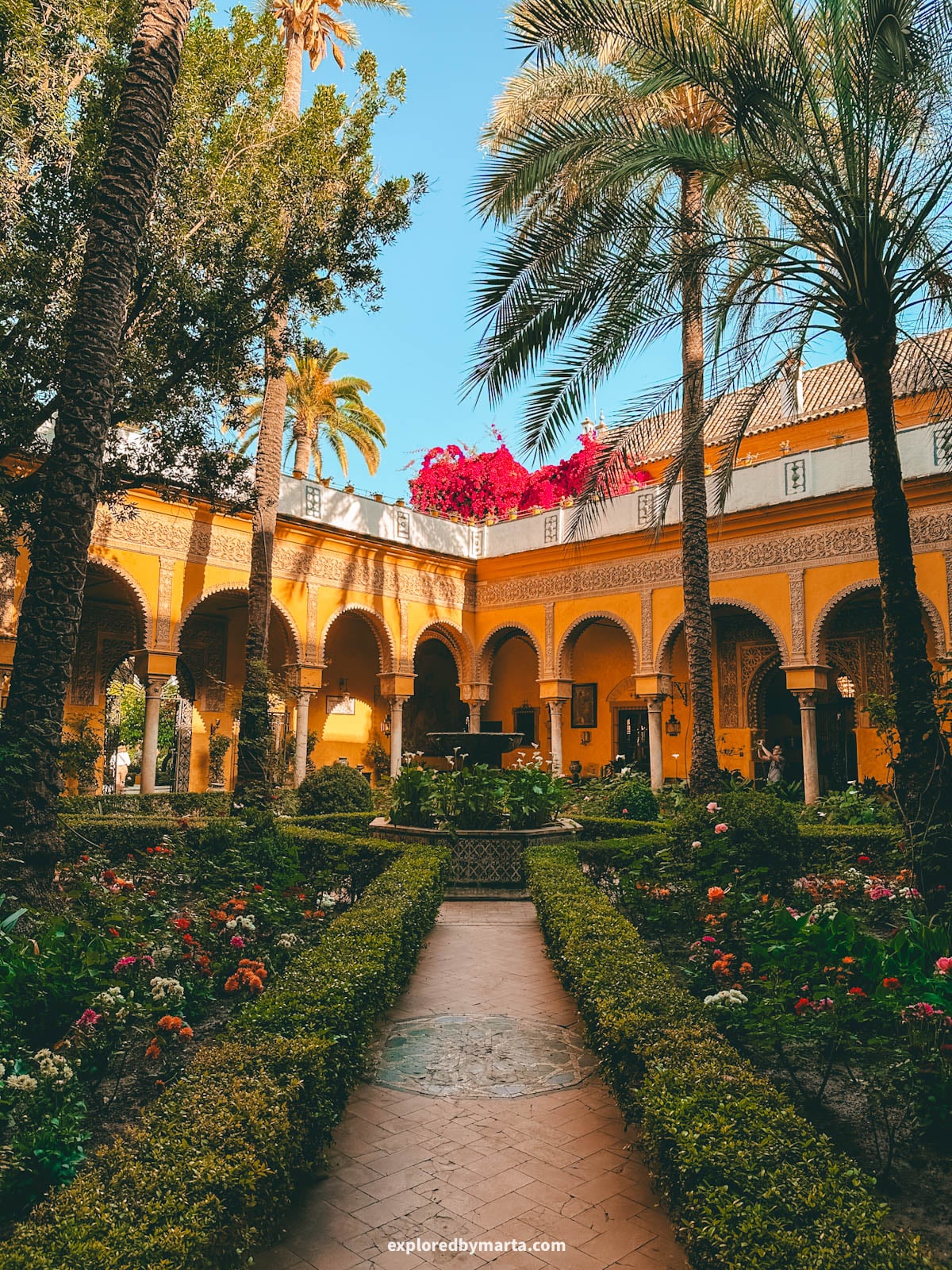 The yellow-arched main patio at Palacio de las Dueñas in Seville, Spain