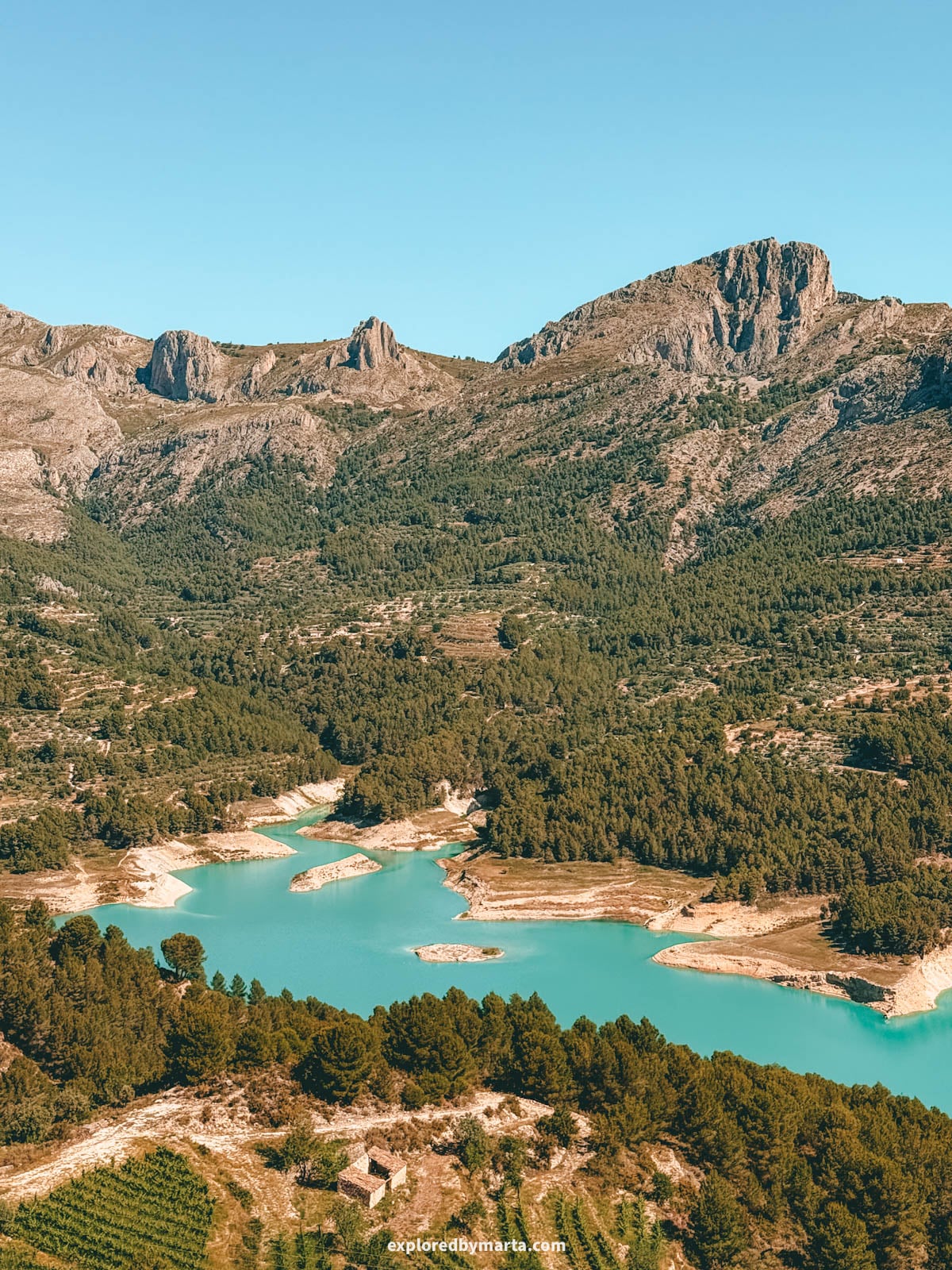 Turquoise reservoir and mountains seen from Plaza de San Gregorio in Guadalest, Spain