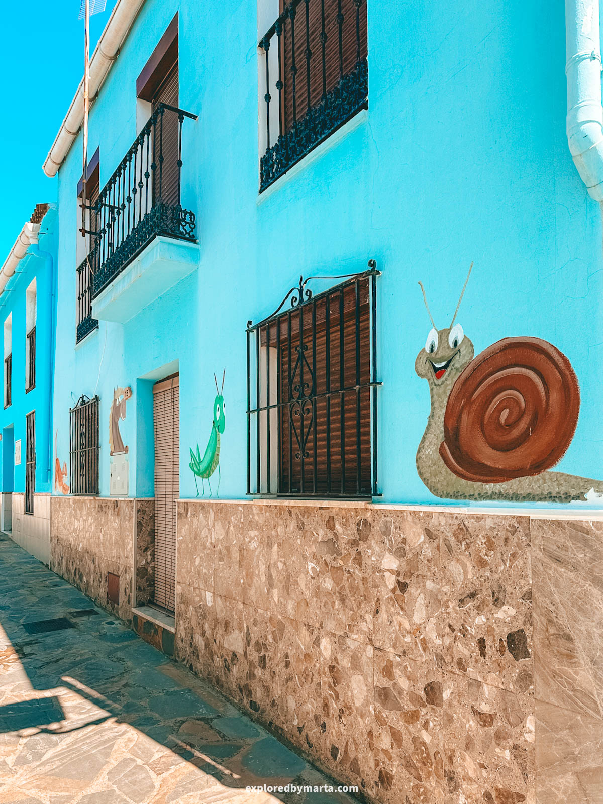 Street art and blue houses on Calle Sol, the prettiest street in Júzcar, Spain