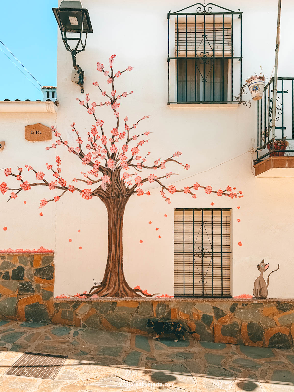 Street art and blue houses on Calle Sol, the prettiest street in Júzcar, Spain